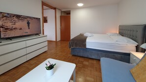 Una habitación de hotel moderna con una cama, televisión, escritorio y una planta en maceta.