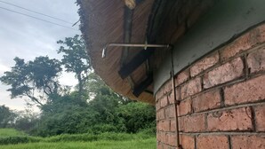 A brick wall with a metal gutter and a thatched roof edge. - Spring Resort  (Hurungwe)