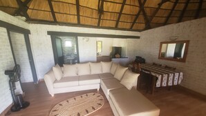 A living room with a sectional sofa, a small table, and a mirror on the wall. - Spring Resort  (Hurungwe)