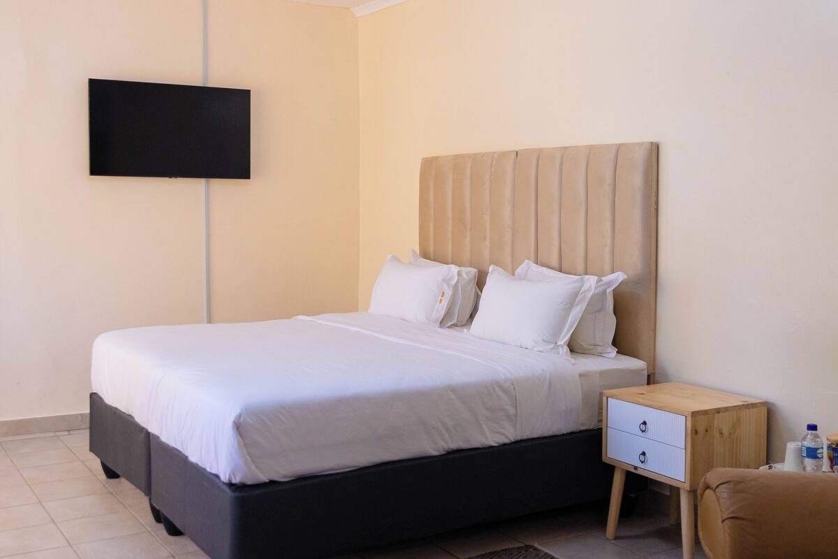 A neatly arranged bedroom with a bed, bedside table, and a TV mounted on the wall.