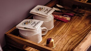 Un plateau en bois avec deux tasses en céramique blanche et un petit objet décoratif.