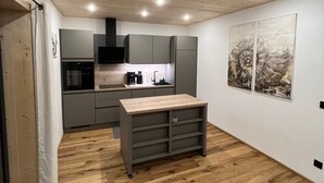 Una cocina moderna con una isla central, armarios grises y suelo de madera.