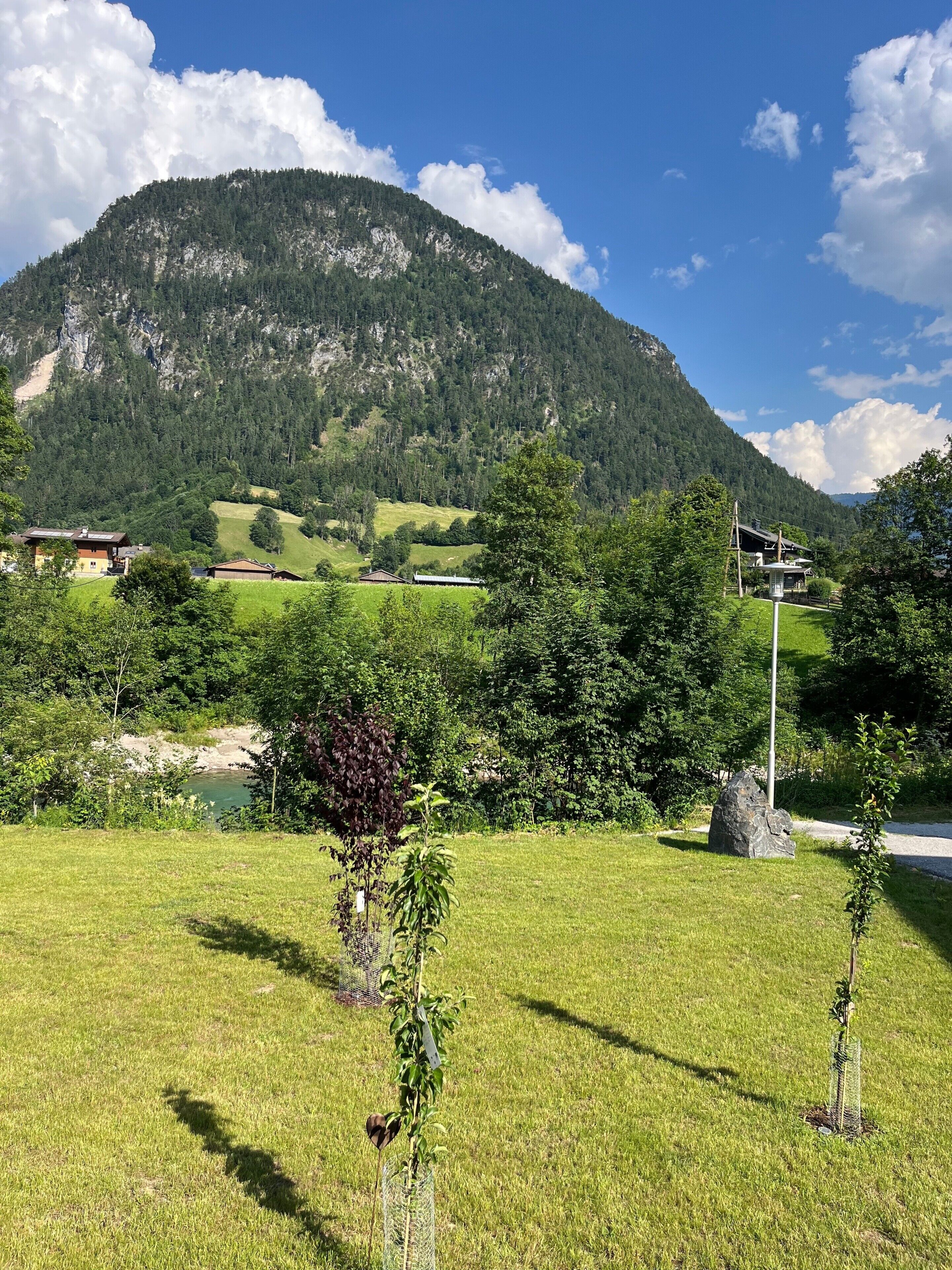 A mountainous landscape with a clear sky, a small body of water, and a few buildings in the distance.