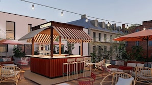 An outdoor bar area with a striped awning, wicker chairs, and a sign that reads 'CORNER'. - Alfred Hotels Montreuil - Hôtel Rénové (Montreuil)