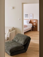 Una habitación con una cama, un sofá y una mesita de noche con una lámpara.