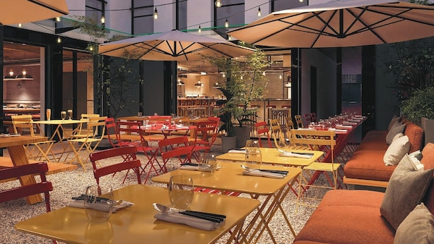 An indoor dining area with tables, chairs, and umbrellas. - Alfred Hotels Montreuil - Hôtel Rénové (Montreuil)