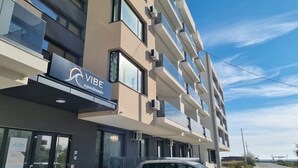 Een modern gebouw met een bord waarop 'VIBE Apartments' staat.