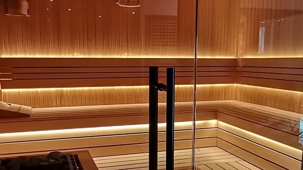 En modern bastu med träpanel och ett centralt placerat värmeelement.