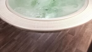 Ett bubbelbad i ett rum med en vägg av marmor och ett mörkt trägolv.