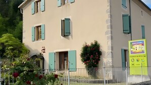 Un bâtiment à deux étages, doté de nombreuses fenêtres, d’un mur en pierre et d’une clôture blanche.