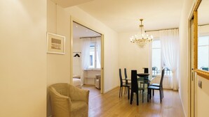 Una habitación amplia con comedor, una araña y un espejo grande.
