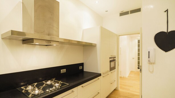 Una cocina moderna con estufa a gas, armarios blancos y encimera negra.