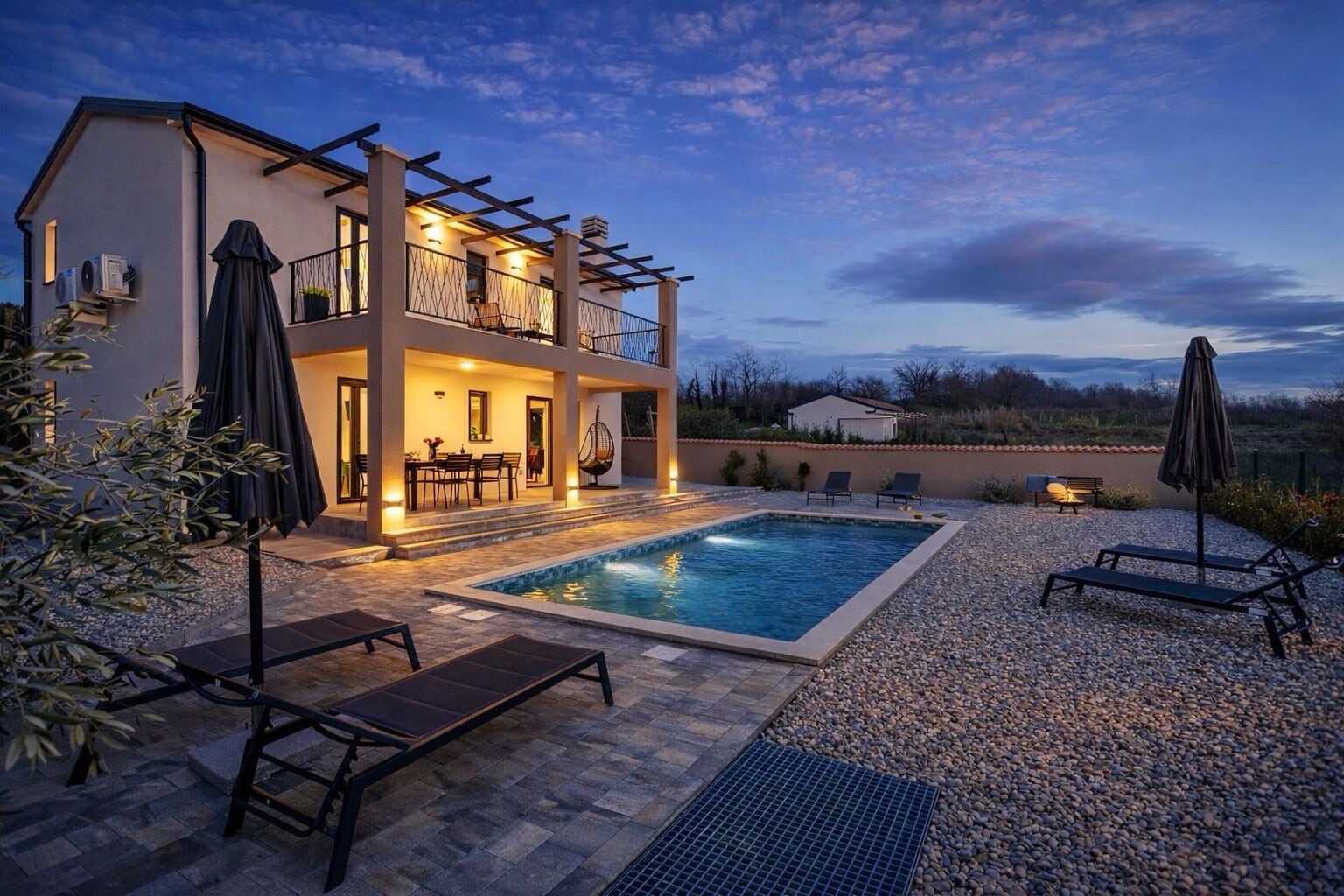 Uma casa de dois andares com piscina, área de estar externa e pérgola.