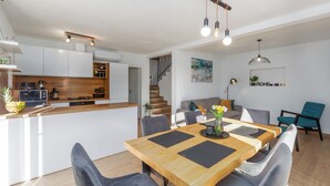 A modern kitchen with white cabinets, a wooden island, and a dining area with a wooden table and grey upholstered chairs. - Villa Lumina Divina-Modern villa with Heated Pool (Prhati)