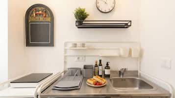 Una cocina moderna con un reloj, una planta, una repisa con tazas y un lavabo.