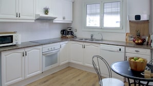 A kitchen with white cabinets, a microwave, a coffee maker, and a window with blinds. - House in Palafolls Near Costa Brava Beaches (Palafolls)