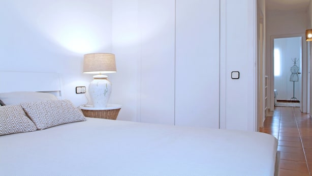 A neatly arranged bedroom with a bed, a bedside lamp, and a wicker basket. - House in Palafolls Near Costa Brava Beaches (Palafolls)