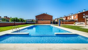 A rectangular swimming pool with a concrete deck, surrounded by a brick building and a grassy area. - House in Palafolls Near Costa Brava Beaches (Palafolls)