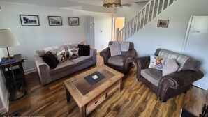 A living room with a sofa, armchair, coffee table, and a staircase. - Cosy, dog friendly, two-bedroom cottage in Hawes. (Hawes)