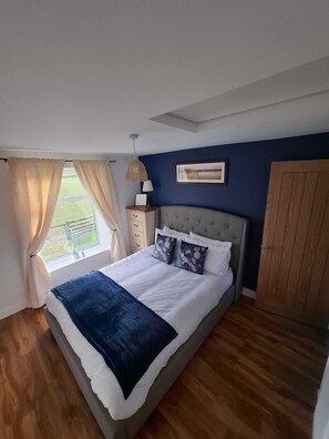 Une chambre à coucher comprenant un lit, une table de chevet, une lampe, un tableau encadré et une armoire.
