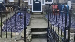 A stone building with a central entrance, a small porch, and a metal gate. - Cosy, dog friendly, two-bedroom cottage in Hawes. (Hawes)