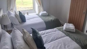 A bedroom with a bed, a window with curtains, a lamp, and a wardrobe. - Cosy, dog friendly, two-bedroom cottage in Hawes. (Hawes)