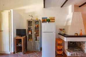 Ein gemütlicher Wohnbereich mit Fernseher, Holzschrank, Kühlschrank und Kamin aus Backsteinen.