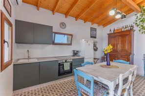 A kitchen with a sink, oven, and cabinets, a dining table with chairs, and a clock on the wall. - Vacation Home 'Casarural El Camino De Tejeda' with Sea View, Wi-Fi and Air Conditioning (Vega de San Mateo)