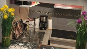 A kitchen with a coffee maker, a sink, and a countertop with a magazine and flowers.
