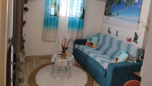 A living room with a blue sofa, a small round table, and a white rug.