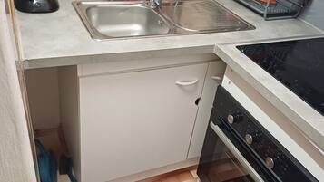 Una cocina compacta con un lavamanos, una cafetera, un escurreplatos y una estufa.