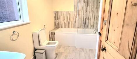 Une salle de bain avec des toilettes, un lavabo et une baignoire.
