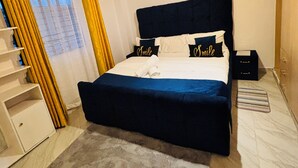 Een slaapkamer met een bed, nachtkastje, lamp en een raam met gordijnen.