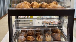 A bakery display case with various pastries and a lower shelf with assorted baked goods. - Floris Hotel (Rende)