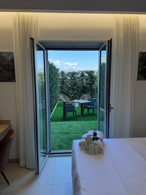 Ein Hotelzimmer mit Bett, Schreibtisch und Blick auf einen Außenbereich mit Tisch und Stühlen.