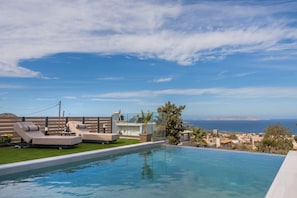 A swimming pool with lounge chairs, a view of the sea, and a clear sky. - Villa Grand Blue (Hersonissos)
