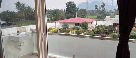 A balcony with a view of a residential area, including a house with a red roof and a garden.