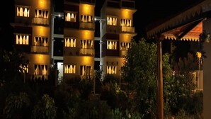 A multi-story hotel with balconies and warm lighting. - Gold Mountain Wellness Resort (Tiruvannamalai)