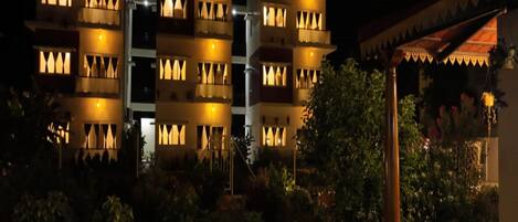 Un hotel de varios pisos con balcones e iluminación cálida.