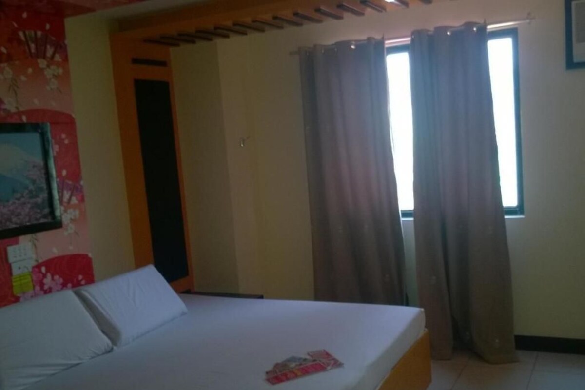 Un dormitorio con cama, ventana con cortinas, puerta y pared con estampado floral.