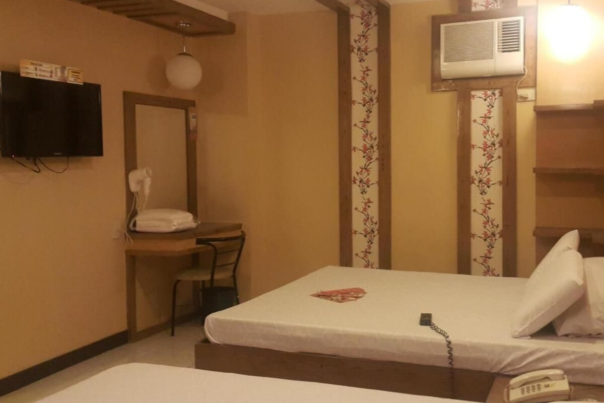 Habitación de hotel con cama, escritorio, silla, teléfono y aire acondicionado.