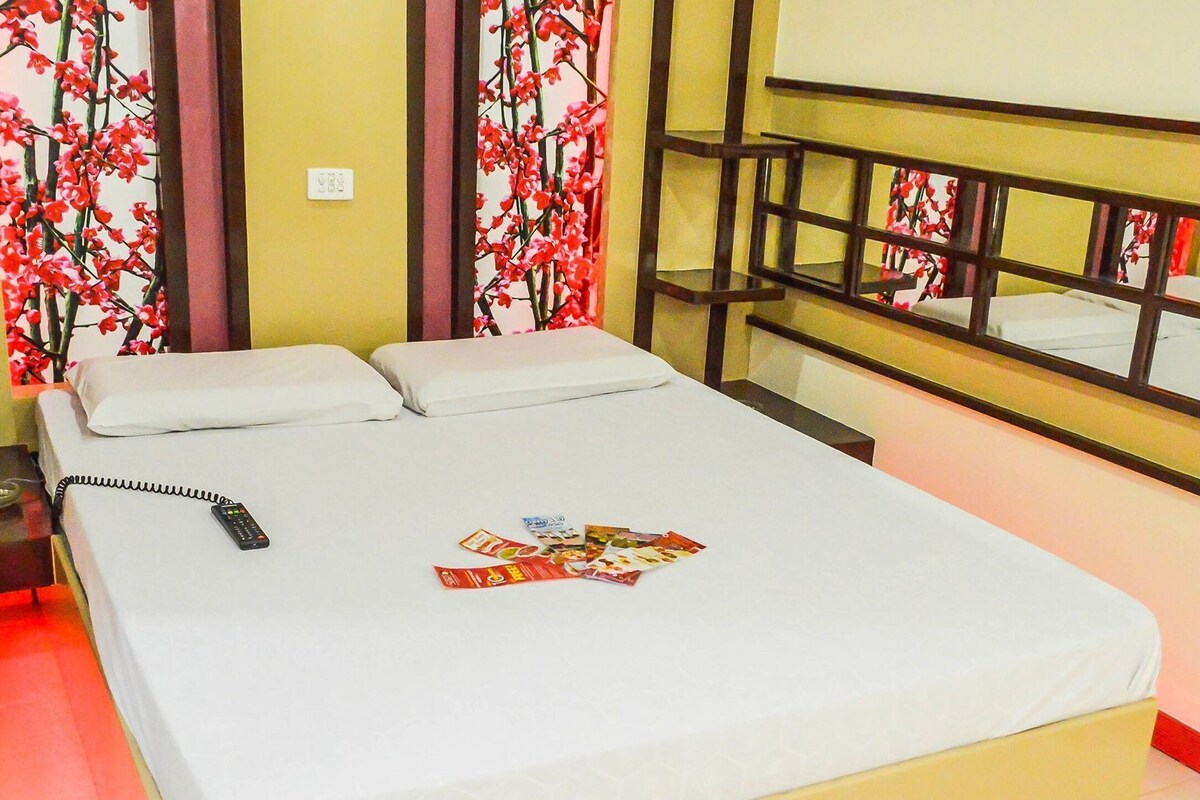 Una habitación de hotel con una cama, un teléfono y una revista sobre la cama.