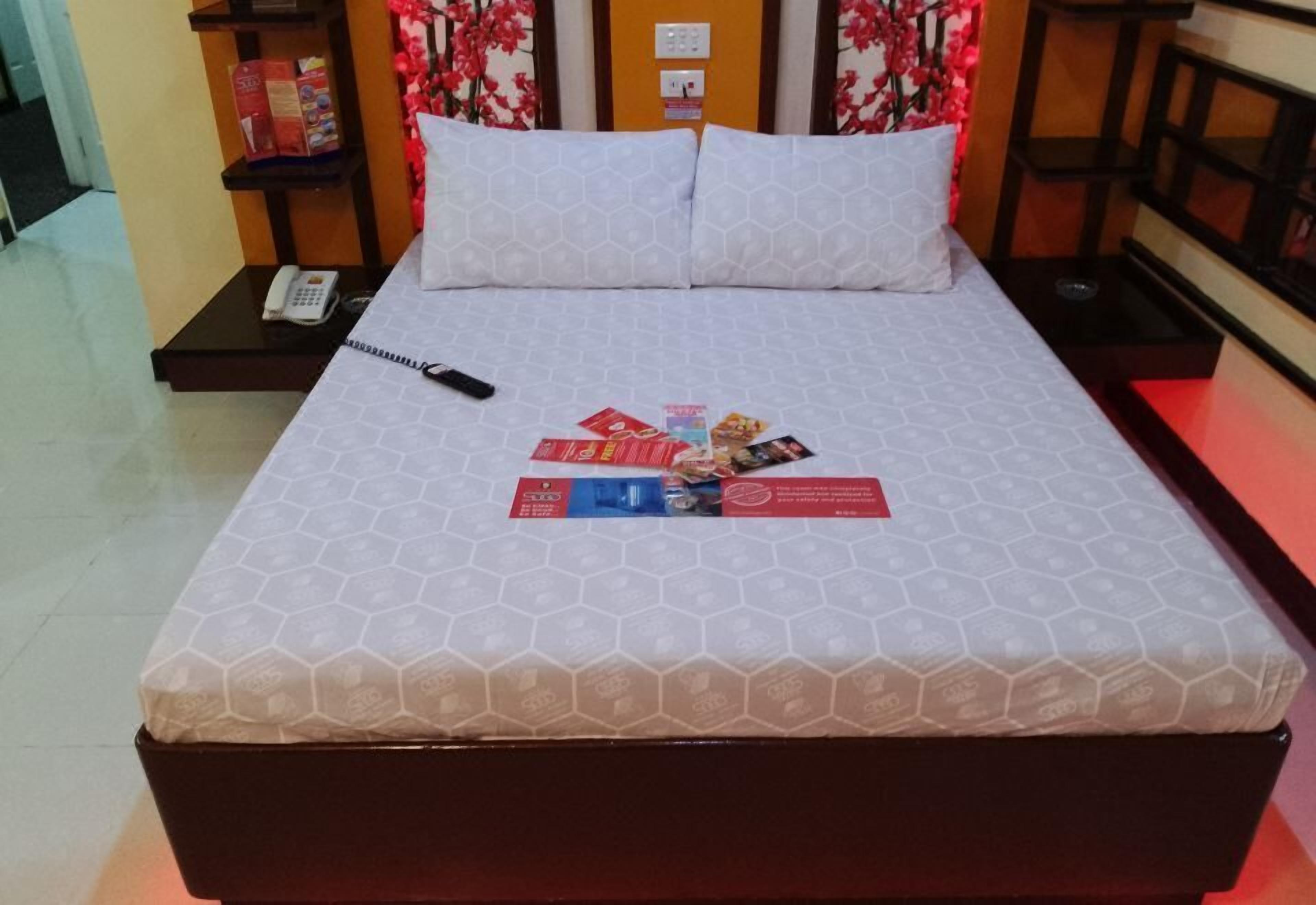 Una habitación de hotel con una cama, una mesita de noche con teléfono y una pared con estampado floral.
