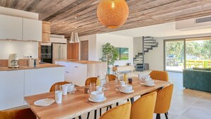 Et moderne køkken med hvide skabe, en træø, og et spiseområde med gule stole og et træbord.