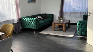 Una sala de estar con un sofá verde, una mesa de centro de madera y una silla amarilla.
