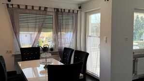 Un comedor con una mesa y sillas, una ventana con persianas y un radiador.