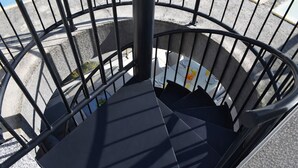A spiral staircase with a metal railing, leading to a room with a white table and chairs. - At469 in Oliva With 2 Bedrooms and 2 Bathrooms (Oliva)