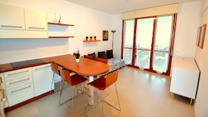 Una cocina moderna con armarios blancos, una mesa de comedor de madera y sillas rojas.