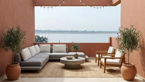 A balcony with a sofa, chairs, a round coffee table, and potted plants. - Saapna Resort & Boat Club (Betūl)