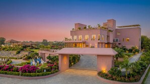 A modern hotel with a pink facade, a central courtyard, and a flag display. - Saapna Resort & Boat Club (Betūl)